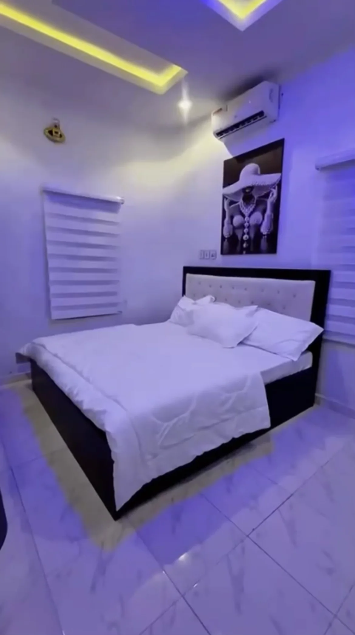 Laimon bedroom with white bedding, a tufted headboard and soft ceiling lighting
