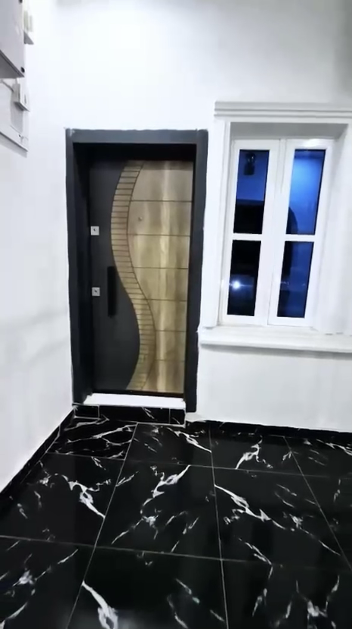 Apartment entrance with decorative door and black marble-look floor